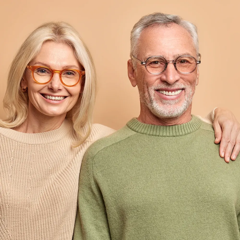 Older couple wearing glasses smiling with healthy teeth