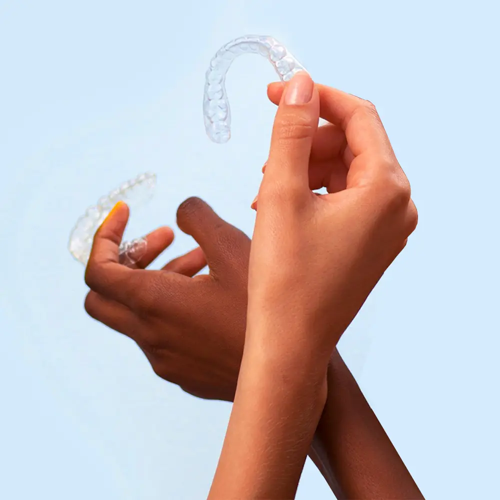 Two hands holding Invisalign clear aligners for cosmetic dentistry